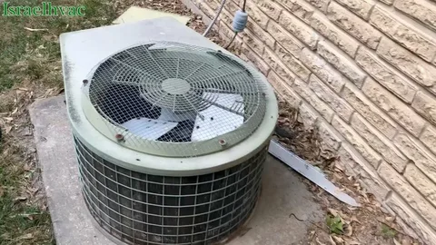 HVAC Running Constantly But Not Cooling in a residential home with a round outdoor air conditioning condenser unit featuring a metal fan grille, installed on a concrete pad beside a beige brick wall.